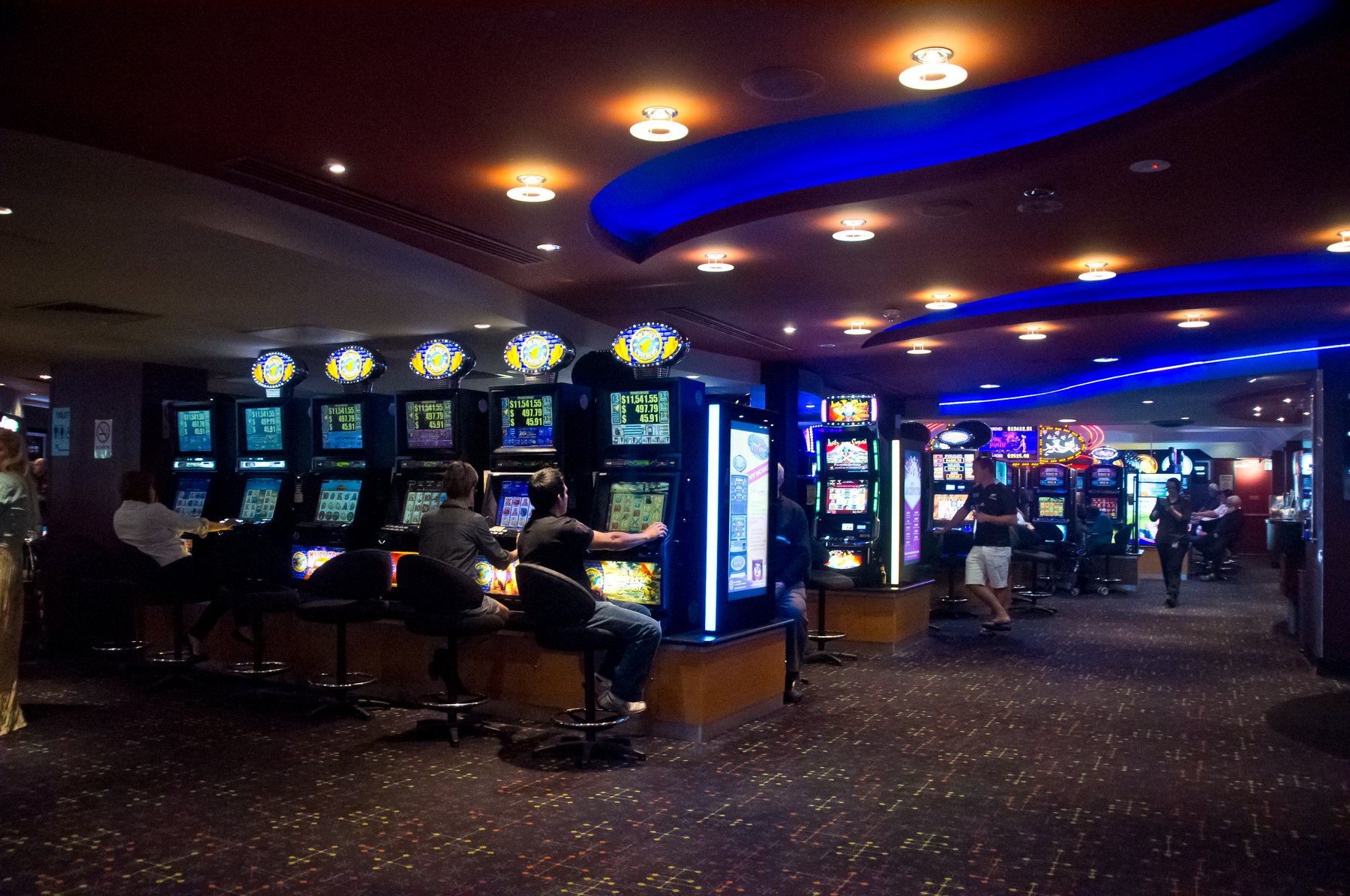 Rows of electronic gaming machines on a carpeted club floor, similar to bar and retail video gaming terminals