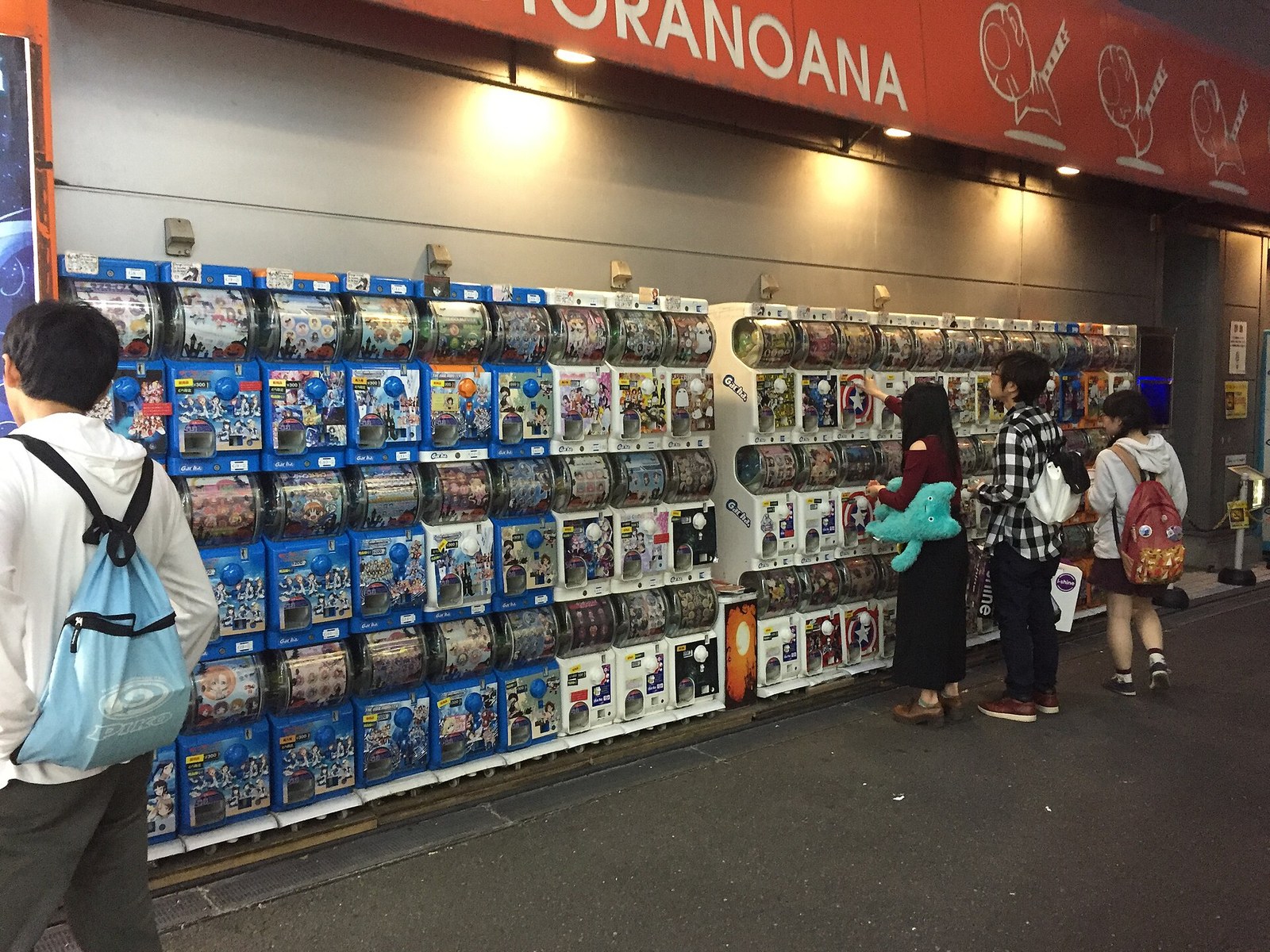 Rows of gashapon capsule-toy vending machines in a public arcade corridor