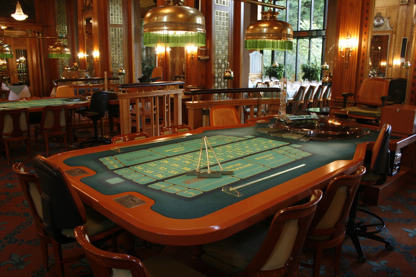 Empty roulette table with green felt and brass lamps inside a historic casino hall Empty roulette table with green felt and brass lamps inside a historic casino hall