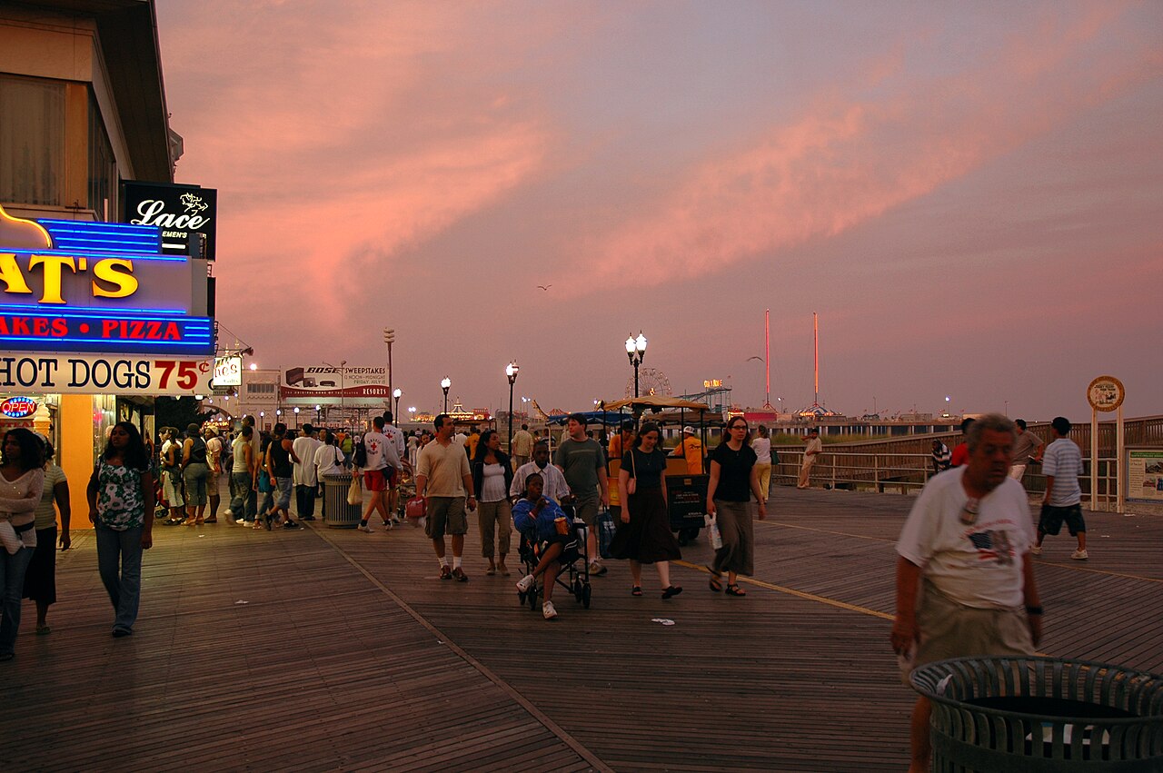 Crowds walking along the Atlantic City Boardwalk at dusk under a pink sky, New Jersey Crowds walking along the Atlantic City Boardwalk at dusk under a pink sky, New Jersey