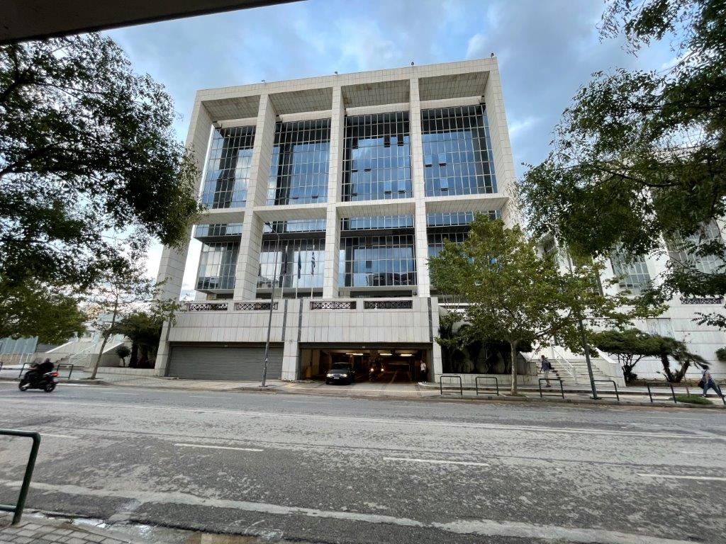 Exterior of the Athens Court of Appeal building, a white modern courthouse with glass facade on a tree-lined street