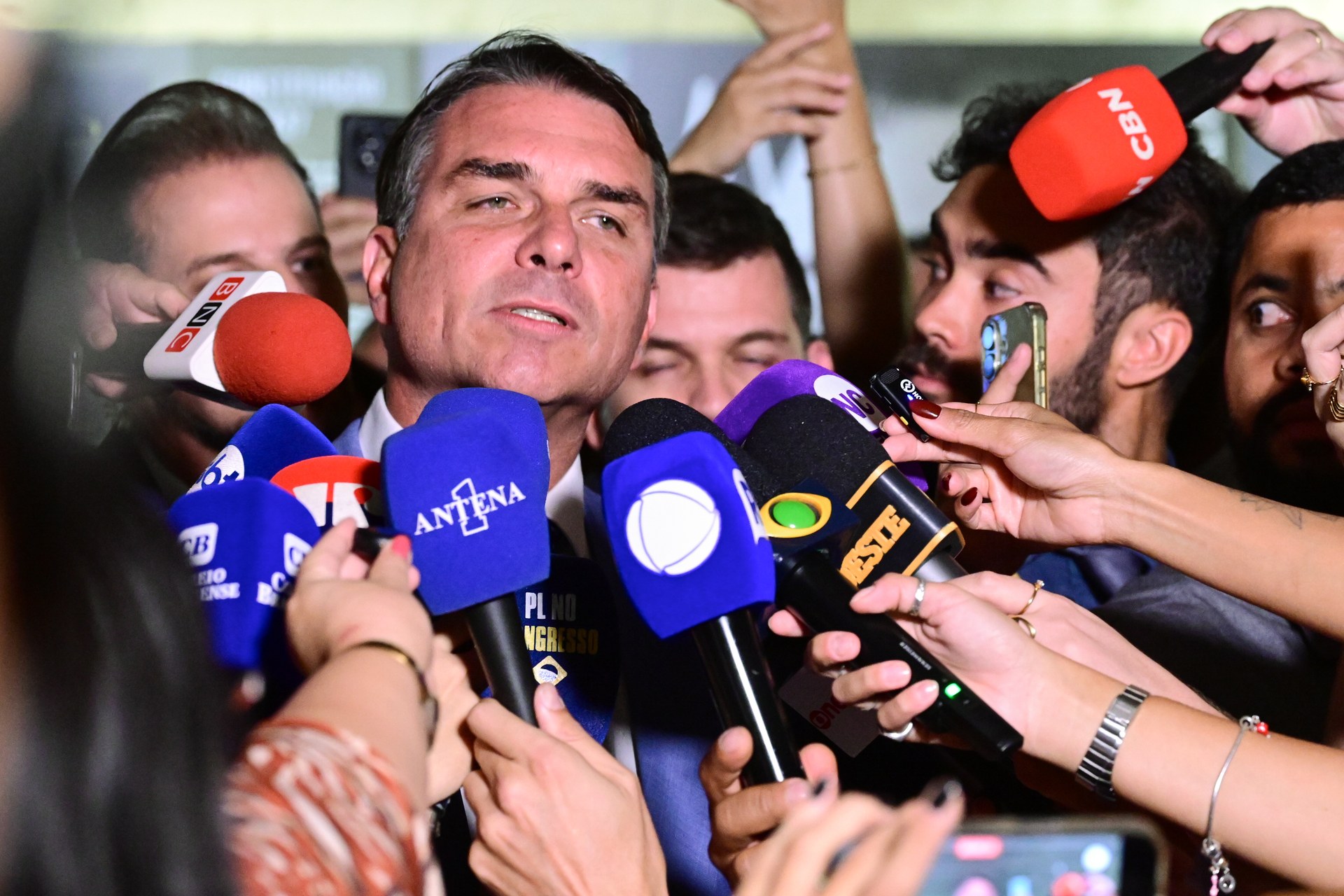 Senator Flávio Bolsonaro speaks to reporters holding microphones at Brazil's Federal Senate